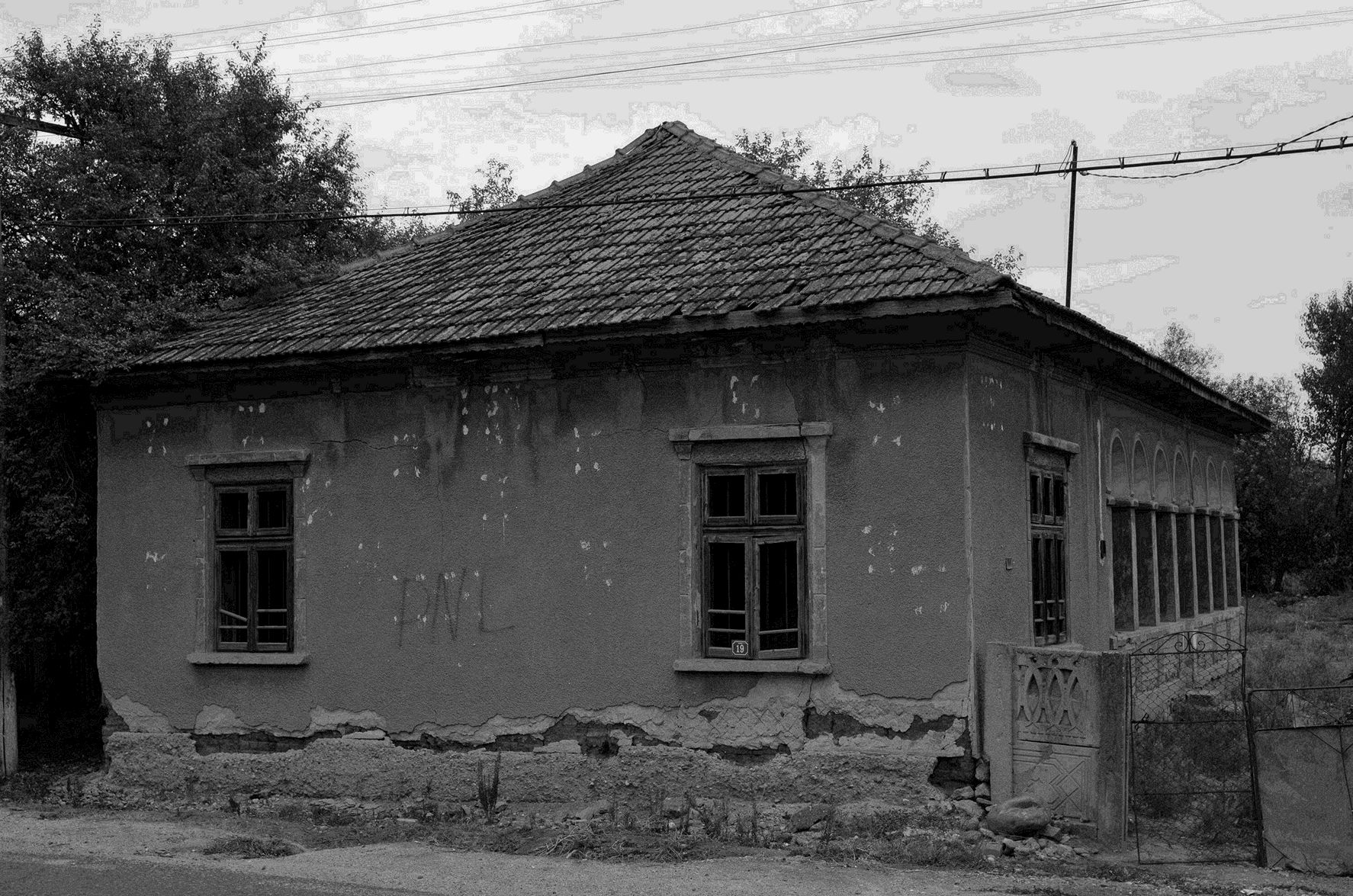 Imaginea unei construcții din pământ bătut, cu peretele parțial deteriorat.