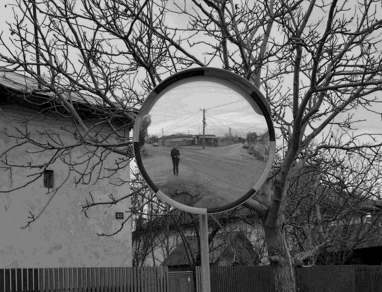 Imaginea unei intersecții de străzi dintr-un sat de câmpie, fotografiată într-o oglindă rutieră, în timpul cercetării de teren.