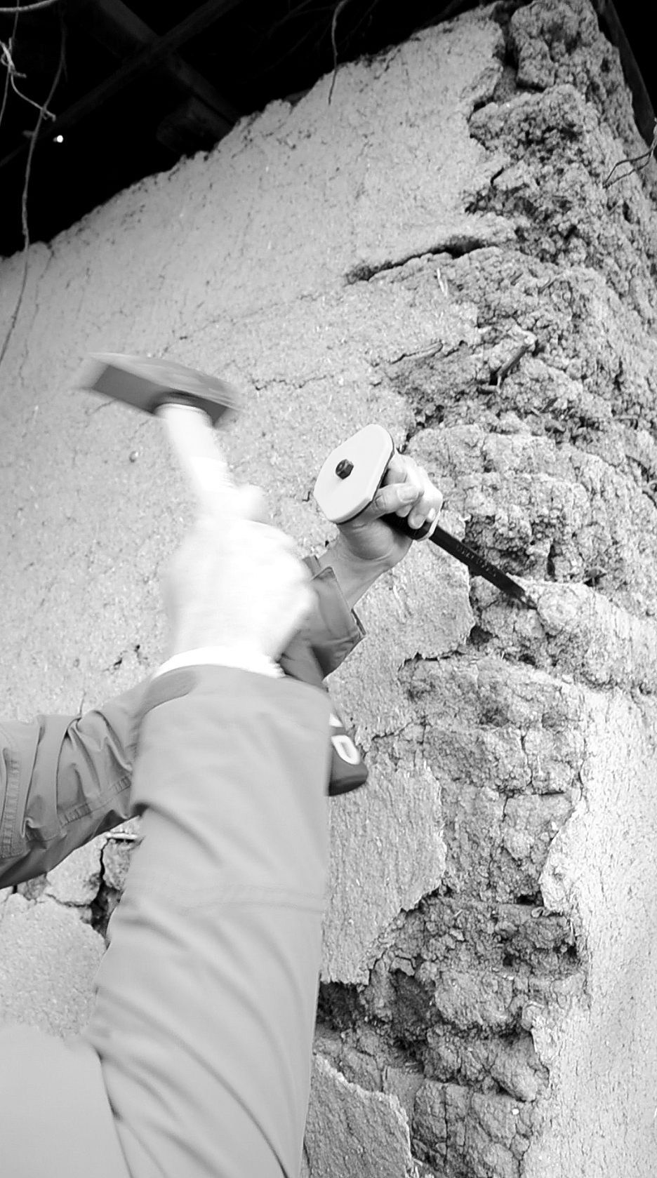 Prelevarea cu ciocanul și dalta a unor probe de la o construcție din pământ bătut.