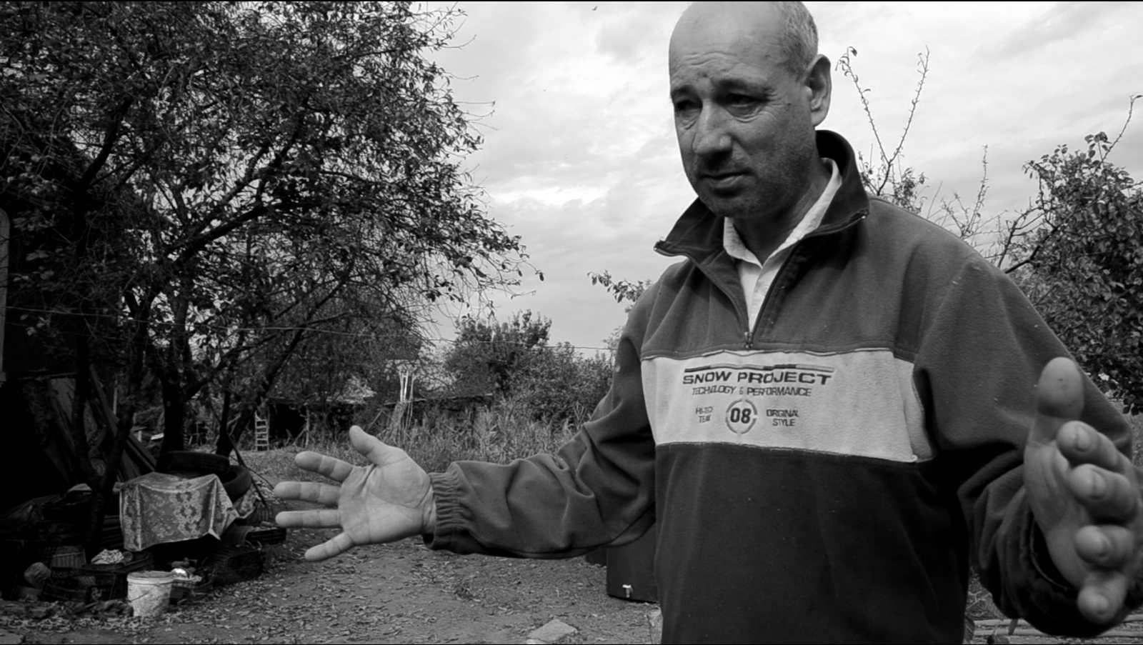 O persoană prezintă modalitatea de construire a caselor din pămât bătut. Imaginea este un stop-cadru dintr-un interviu cu locuitorii satelor din zona cercetată.